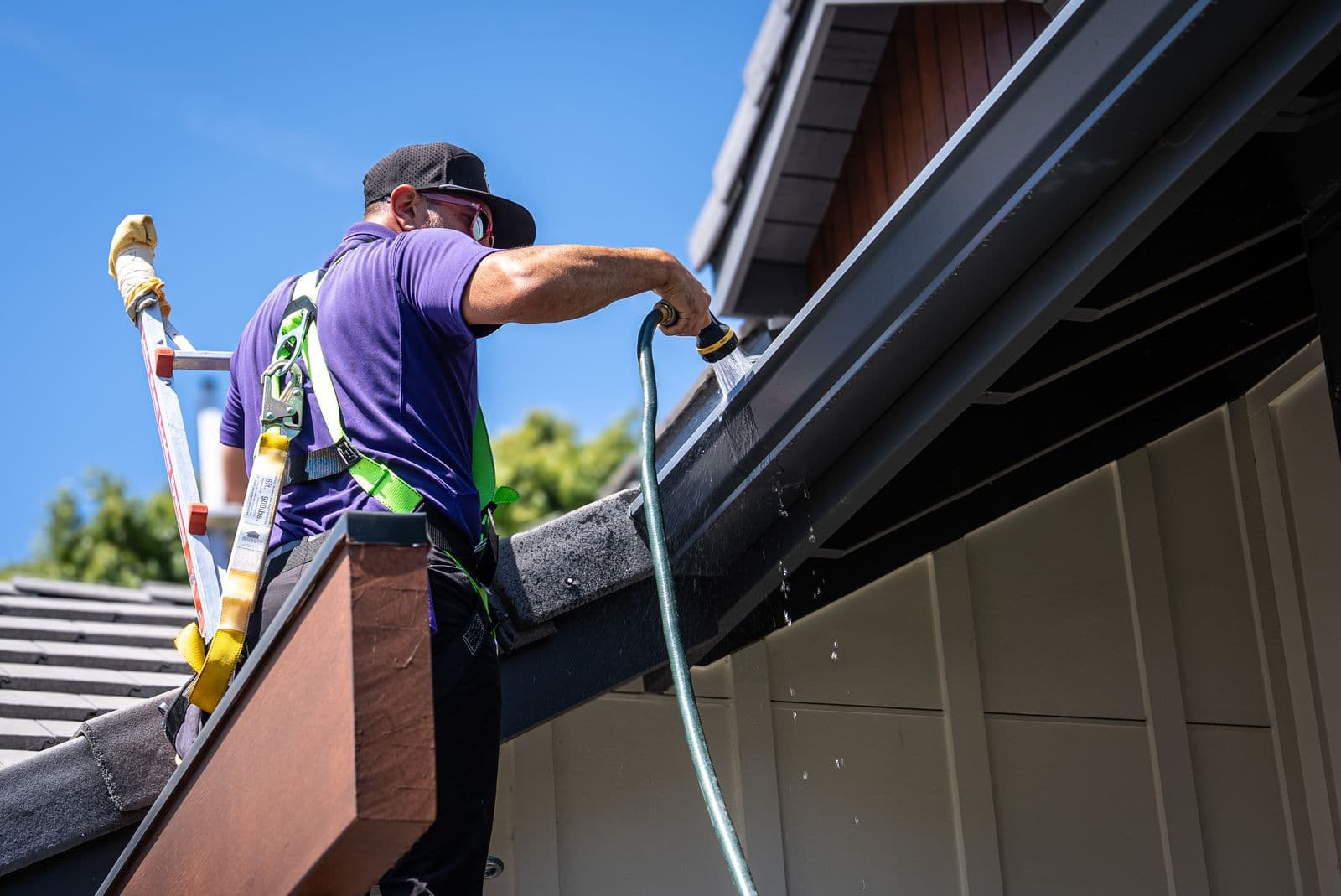RadPad technician flushing a gutter and downspout from the roofline