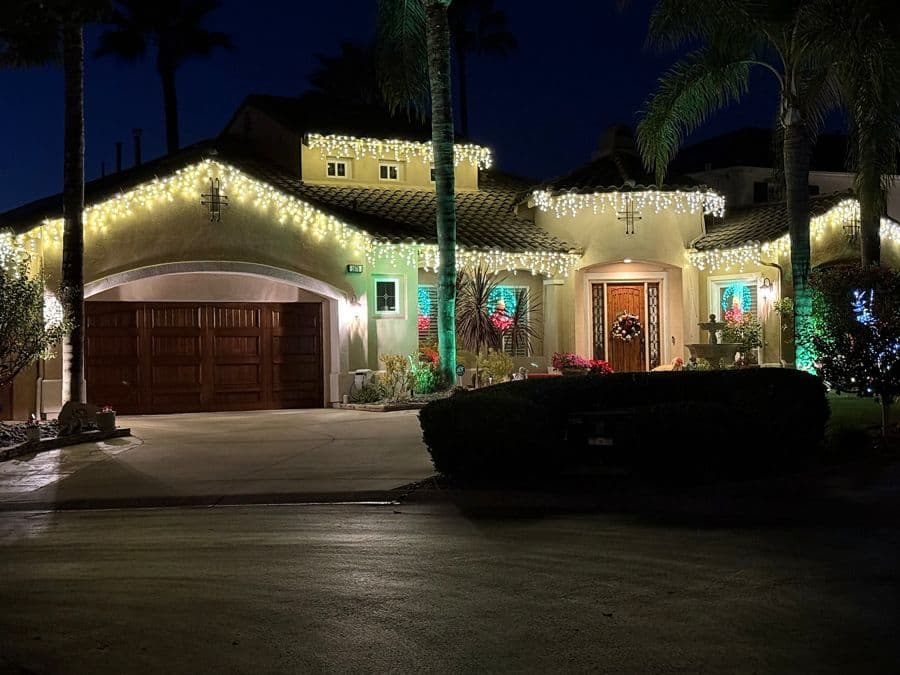 Holiday lighting installed along a home's roofline at night