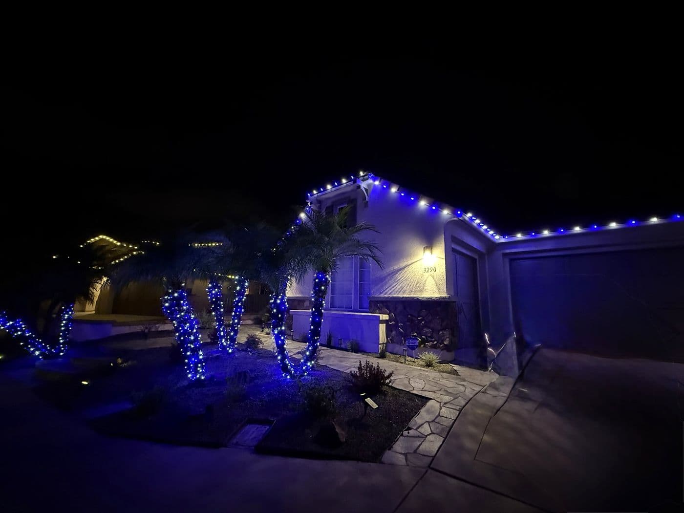 Blue holiday lights on a home and front yard trees