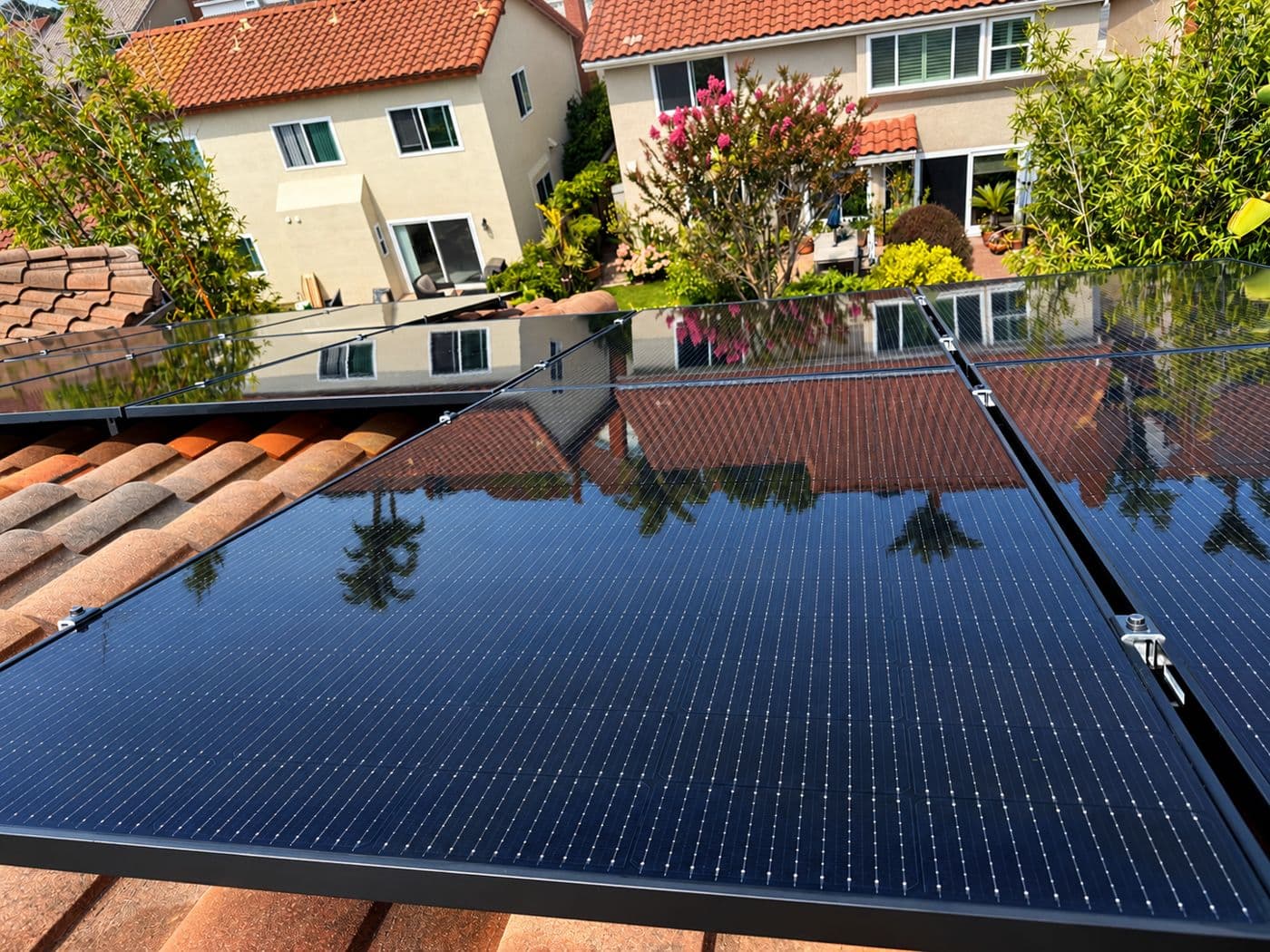 Solar panels on a tile roof, clean enough to reflect the trees