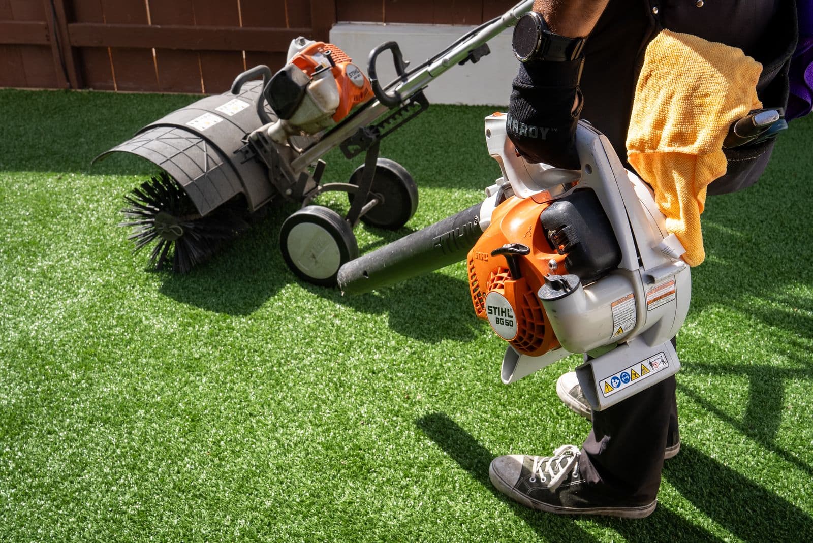RadPad technician with power broom and blower on artificial turf