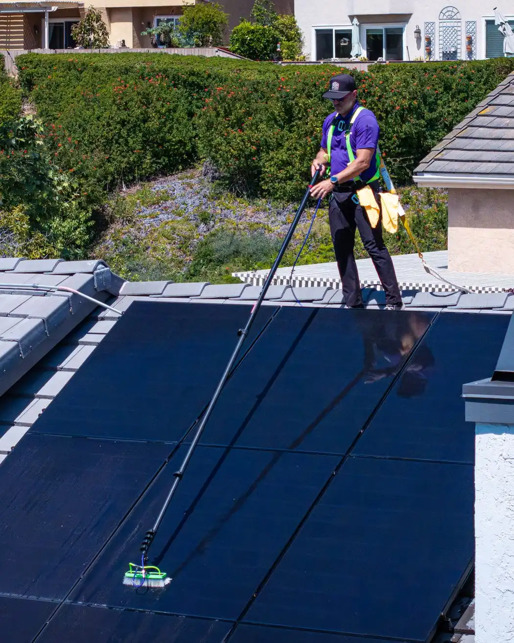 Aerial view of a RadPad technician cleaning a rooftop solar array on a San Diego home